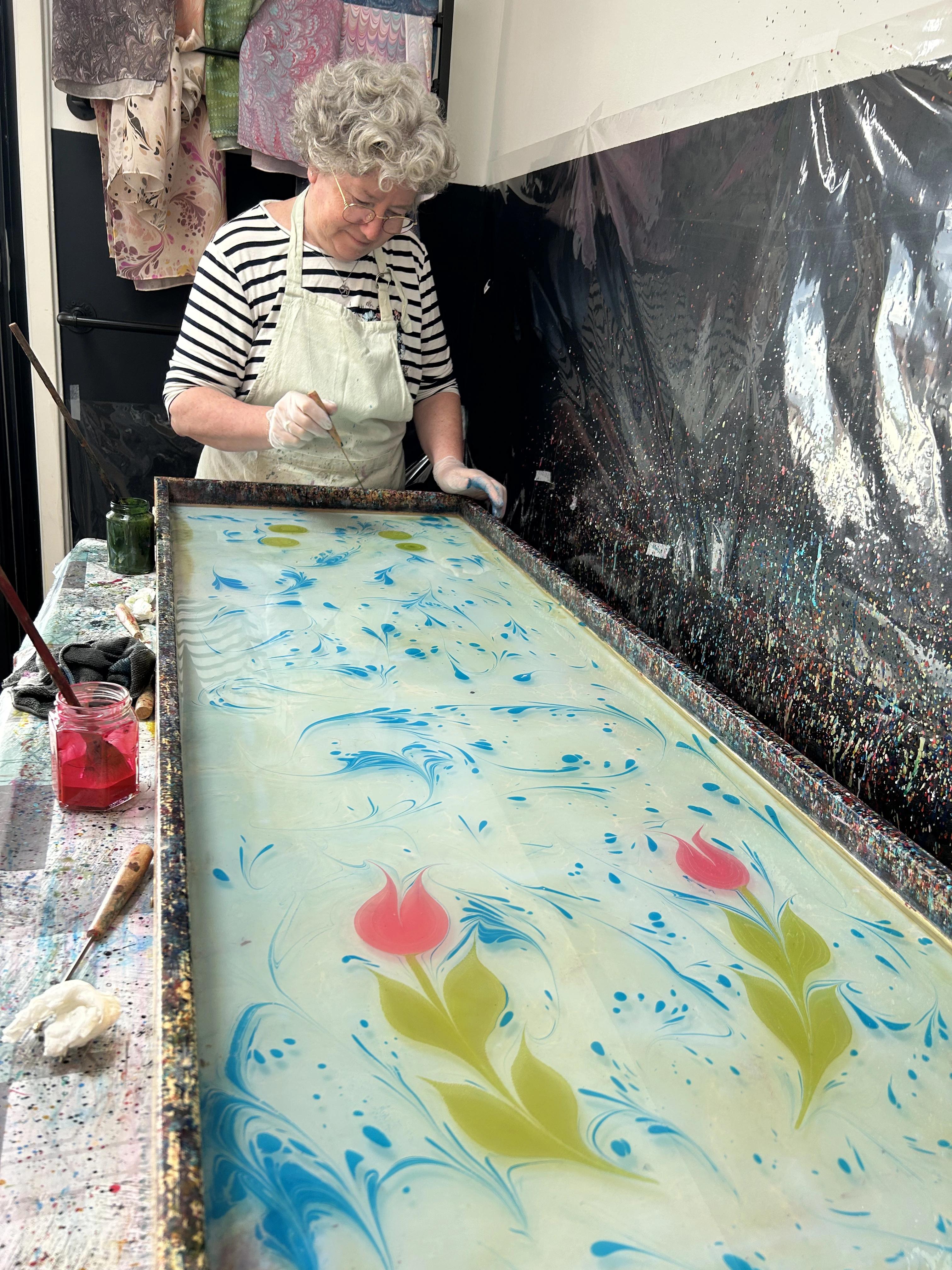 Een vrouw die geconcentreerd bezig is met ebru kunst