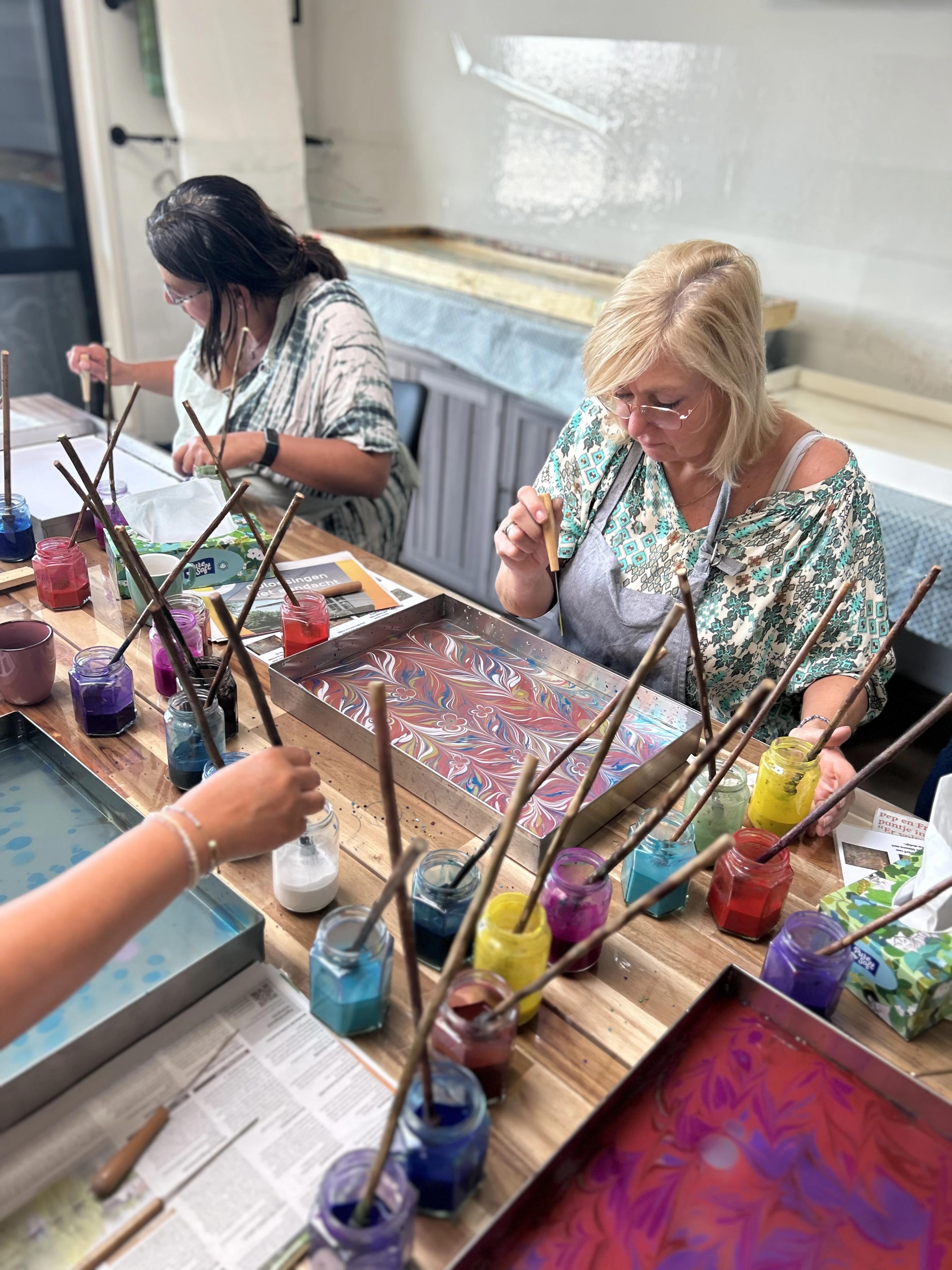 Een vrouw die geconcentreerd bezig is met ebru kunst